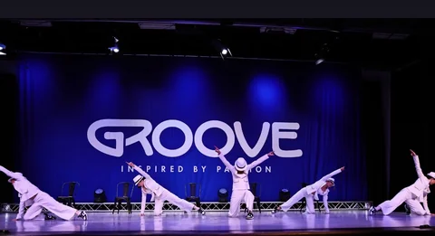 Dance ensemble in white suits and hats performing together