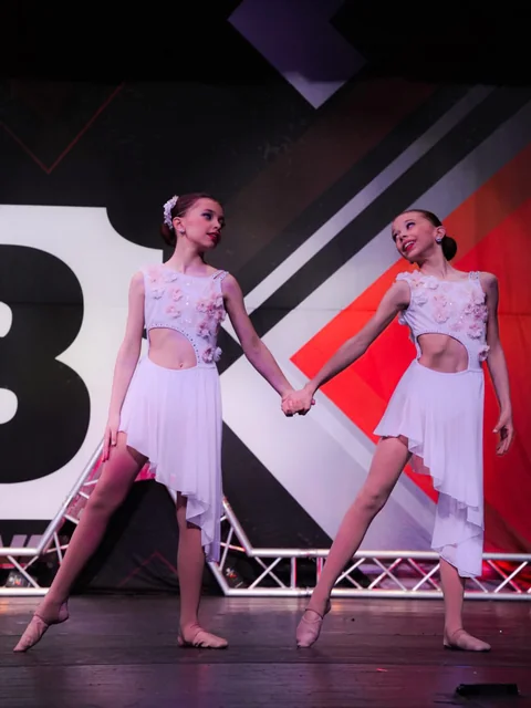 Two dancers in white costumes performing a duet