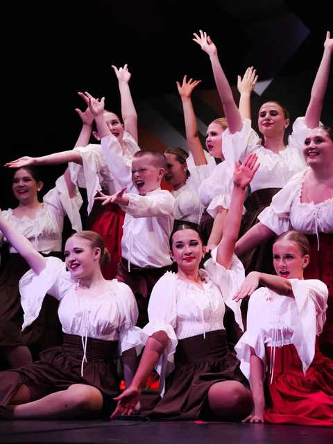 Dance ensemble in white blouses celebrating a stage moment