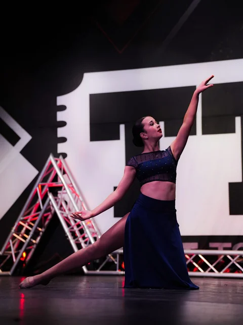 Solo dancer in a navy costume reaching upward