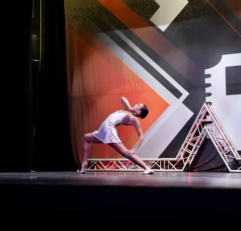 Solo dancer in white holding an expressive stage pose