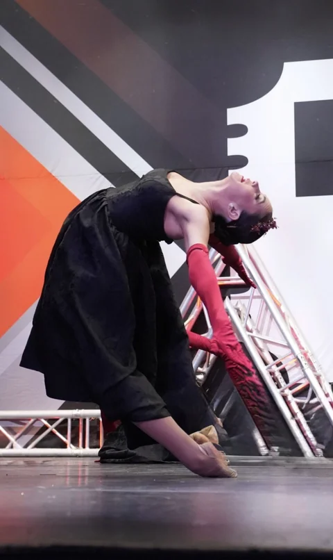Solo dancer in black with red gloves performing a backbend