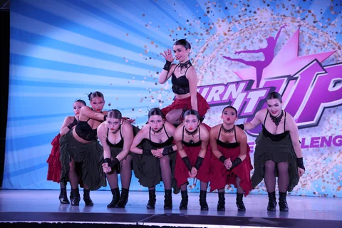 Dance ensemble in black and red costumes performing together