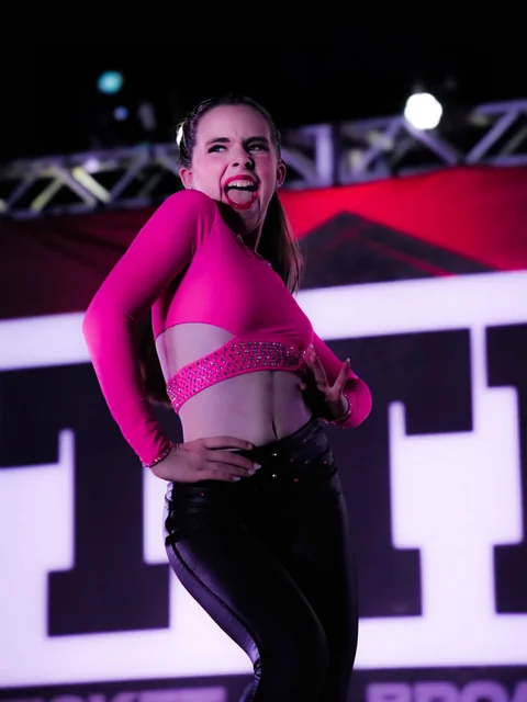 Solo dancer in a bright pink costume performing on stage