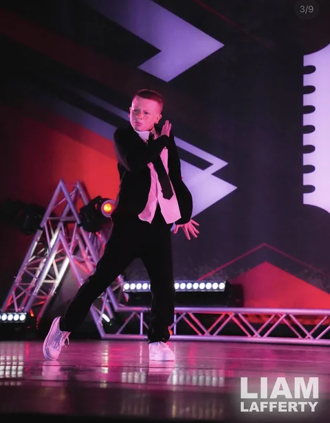 Solo dancer in a black suit performing on stage