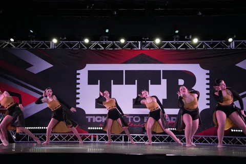 Dance ensemble in gold and black costumes performing together